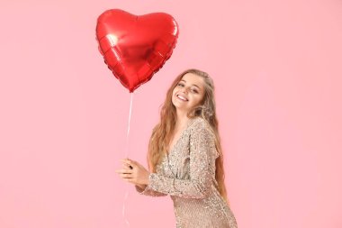 Pembe arka planda kalp şeklinde balonu olan mutlu genç bir kadın. Sevgililer Günü kutlaması
