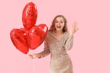 Happy young woman with heart-shaped balloons and engagement ring on pink background. Valentine's Day celebration
