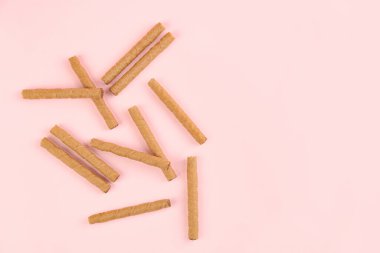 Tasty wafer rolls on pink background