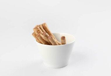 Bowl of tasty wafer rolls with condensed boiled milk on grey background