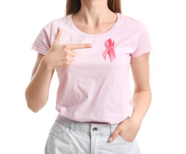 Young woman in t-shirt pointing at pink ribbon on white background. Breast cancer awareness concept