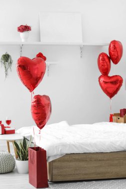 Interior of bedroom decorated for Valentine's Day with red balloons and gifts