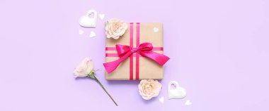 Composition with beautiful gift, decor and flowers on lilac background. Valentine's Day celebration