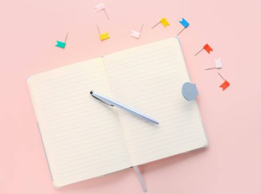 Open notebook, pen and pins on pink background