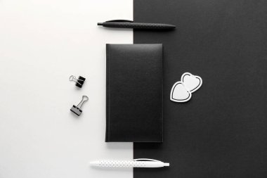 Notebook with pens on black and white background