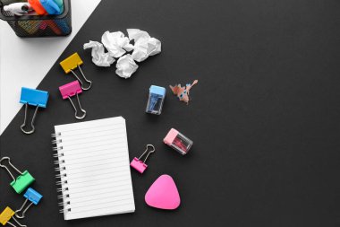 Set of stationery with notebook and crumpled paper on dark background