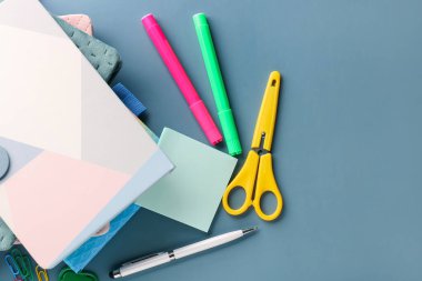 Stack of notebooks and different stationery on color background