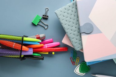 Stack of notebooks and different stationery on color background