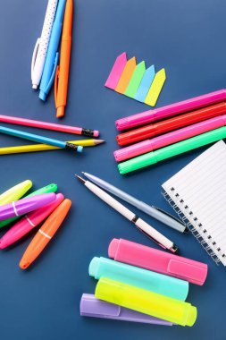 Set of different stationery with markers on color background