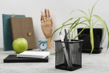 Notebooks, green apple,   stationery holder, clock and plant on grunge background