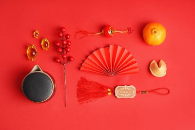 Composition with teapot, mandarin, fortune cookie and Chinese symbols on red background
