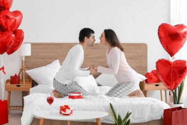 Young couple holding hands in bedroom on Valentine's Day