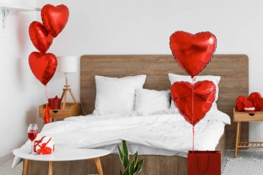 Interior of bedroom decorated for Valentine's Day with red balloons and gifts