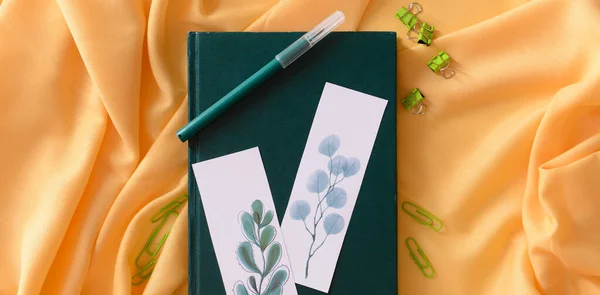 Green book with beautiful bookmarks and stationery on yellow cloth