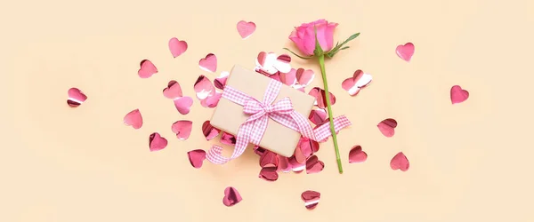 Beautiful composition with gift box, confetti and rose flower on beige background. Valentine\'s Day celebration