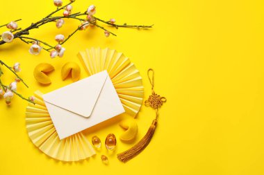 Envelope with fortune cookies, sakura and Chinese symbols on yellow background. New Year celebration