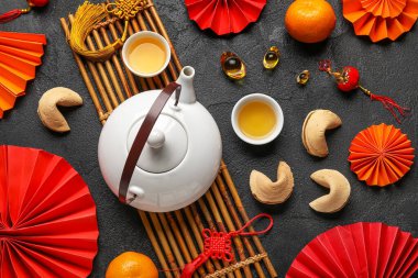 Fortune cookies with teapot, cups and Chinese symbols on dark background. New Year celebration