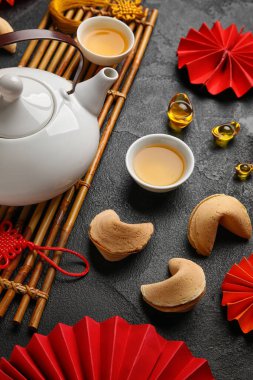Fortune cookies with teapot, cups and Chinese symbols on dark background. New Year celebration
