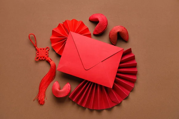 Red envelope with fortune cookies and Chinese symbols on brown background. New Year celebration