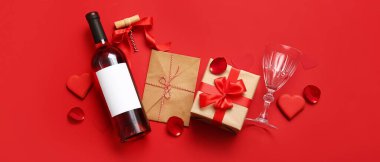 Composition with bottle of wine, glass, letter and gift for Valentines Day on red background
