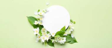 Blank card and beautiful jasmine flowers on green background