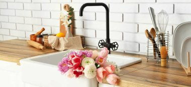 Sink with beautiful bouquet of fresh flowers in interior of modern kitchen