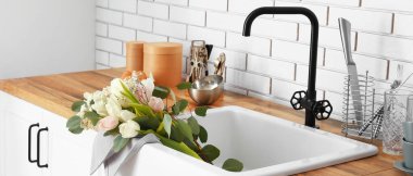 Ceramic sink with beautiful bouquet of flowers in interior of modern kitchen