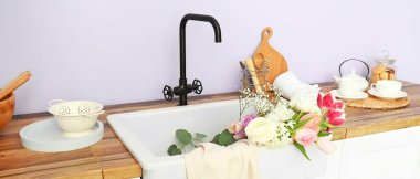 Clean sink with beautiful bouquet of fresh flowers in modern kitchen
