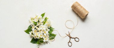 Beautiful jasmine flowers, rope and scissors on light background
