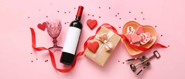 Composition with bottle of wine, glass, cookies and gift for Valentine's Day on pink background