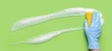 Hand with sponge cleaning green surface