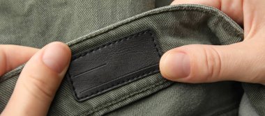 Hands with label on new clothes, closeup