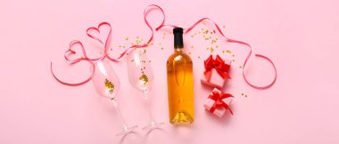 Composition with bottle of wine, glasses and gifts for Valentine's Day on pink background