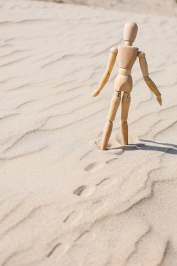 Wooden mannequin on sand, back view