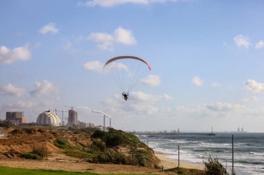 Skydiver flying with parachute near sea