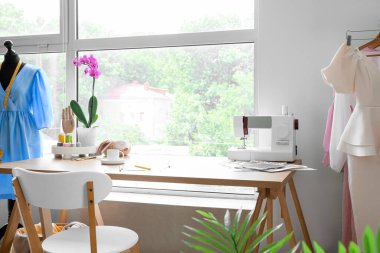 Tailor's workplace with sewing machine and supplies near window