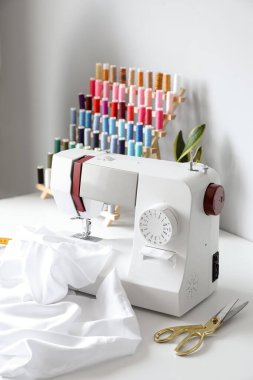 Sewing machine with cloth and scissors on table of seamstress in atelier