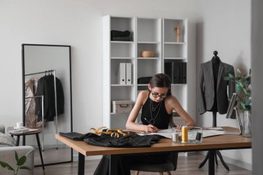 Female dressmaker working at table in modern atelier