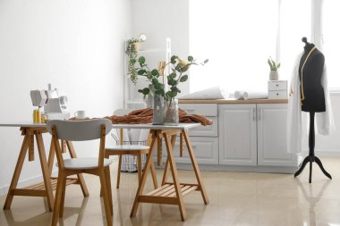 Tailor's workplace with sewing machine and cloth in light atelier