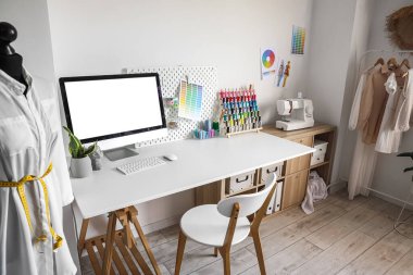 Tailor's workplace with computer and threads in modern atelier