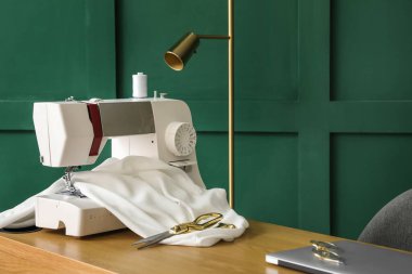 Sewing machine with cloth and scissors on table in atelier