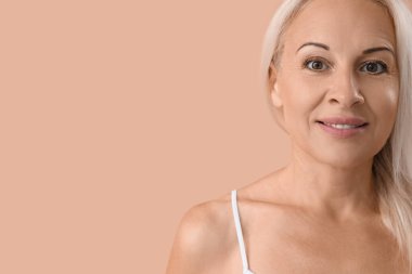 Mature blonde woman on beige background, closeup