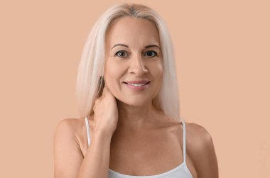 Mature blonde woman on beige background, closeup