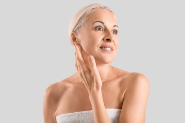 Mature blonde woman smiling on light background