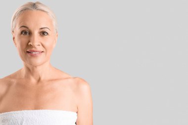 Mature blonde woman smiling on light background