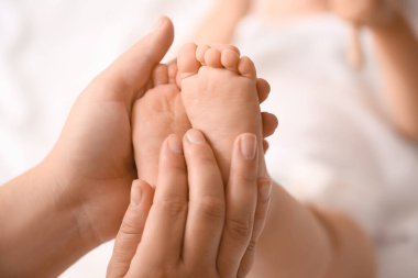 Mother massaging her baby's feet in bedroom, closeup