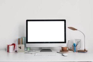 Işık duvarının yanında bilgisayar, bardak ve Noel hediyeli işyeri