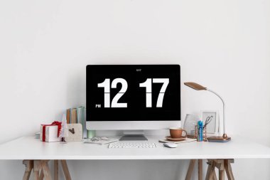 Işık duvarının yanında bilgisayar, bardak ve Noel hediyeli işyeri