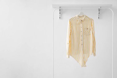 Rack with striped shirt near light wall