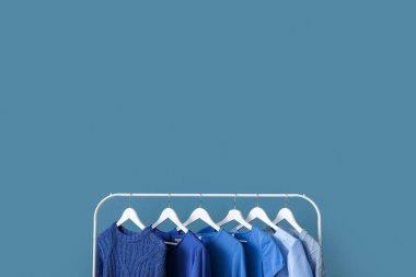 Rack with blue clothes near color wall